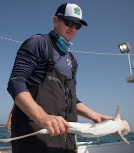 F. Joel Fodrie holds a shark on a boat